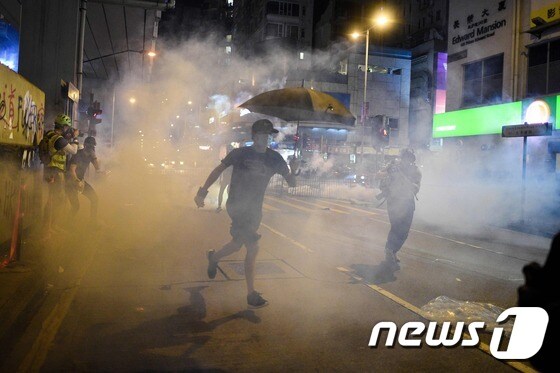몽콕 지역에서 복면금지법을 반대하는 시위대가 경찰의 최루가스를 피하고 있다. © AFP=뉴스1 © News1 우동명 기자