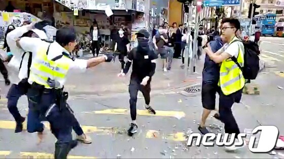 11일(현지시간) 홍콩 사이완호 지역에서 경찰관이 시위대를 향헤 실탄을 쏘고 있다. 경찰은 이날 시위대를 검거하는 과정에서 몸싸움을 벌이다가 다른 시위대가 다가오자 그를 향해 실탄을 발사했다. © 로이터=뉴스1 © News1 우동명 기자