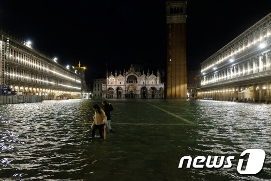 12일(현지시간) 물에 잠긴 이탈리아 베네치아 산마크로 광장을 지나가는 사람들. © 로이터=뉴스1