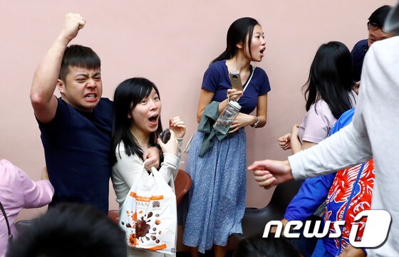 25일 홍콩 사우스호라이즌구 투표소에서 범민주 진영 지지자들이 선거에서 승리하자 환호하고 있다. © 로이터=뉴스1