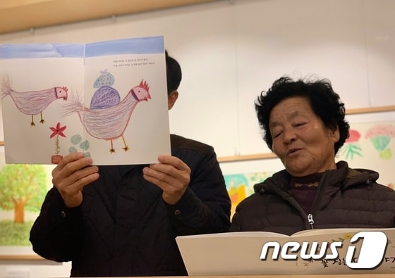 '꽃 심는 닭 이야기'를 쓴 박송자 할머니가 방문객을 위해 직접 책을 읽어 주고 있다.© 뉴스1 