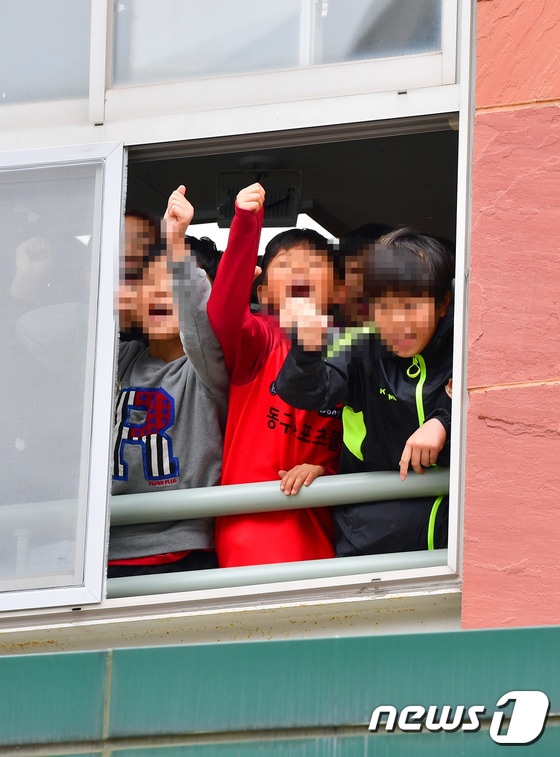 전두환 전 대통령이 5·18 민주화운동 관련 피고인 신분으로 11일 광주지방법원에 들어서는 모습을 인근 초등학교 학생들이 바라보며 