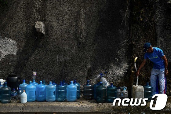 지난 3월13일(현지시간) 대규모 정전사태로 급수가 중단되자 베네수엘라 카라카스의 주민들이 아빌라 국립공원에서 물을 받고 있다. © AFP=뉴스1 © News1 우동명 기자
