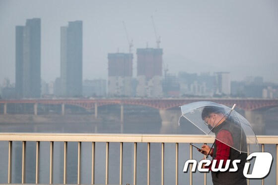 수도권 미세먼지 비상저감조치가 엿새째 이어지고 있는 6일 서울 동호대교 남단에서 마스크를 착용한 시민이 우산을 쓰고 걸어가고 있다. 2019.3.6/뉴스1 © News1 유승관 기자
