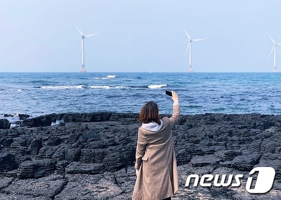 신창 해안도로에서 풍력발전기를 바라보며 여행객이 사진을 찍고 있다© 뉴스1 