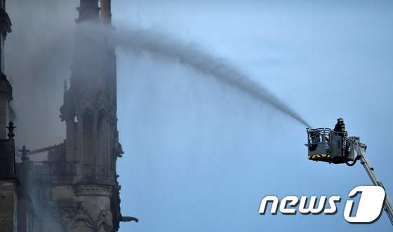 소방대원이 고가사다리를 이용, 노트르담 대성당 첨탑 부근의 화재를 진압하고 있다. © AFP=뉴스1