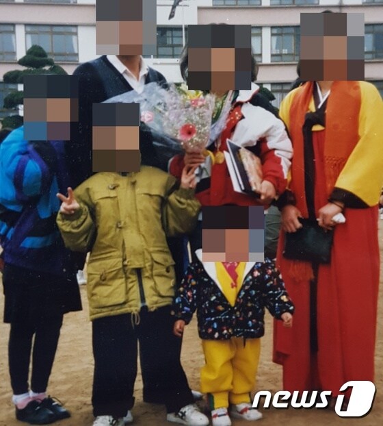 예비신부 큰언니의 중학교 졸업식 당시 온 가족이 함께 찍은 사진. 예비신부가 노란색 저고리 옷을 입고 맨 앞 중앙에 서 있다.(유가족 제공) /© 뉴스1