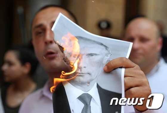조지아 수도 트빌리시에서 반러시아 시위대가 블라디미르 푸틴 러시아 대통령 사진에 불을 붙이고 있다. © 로이터=뉴스1