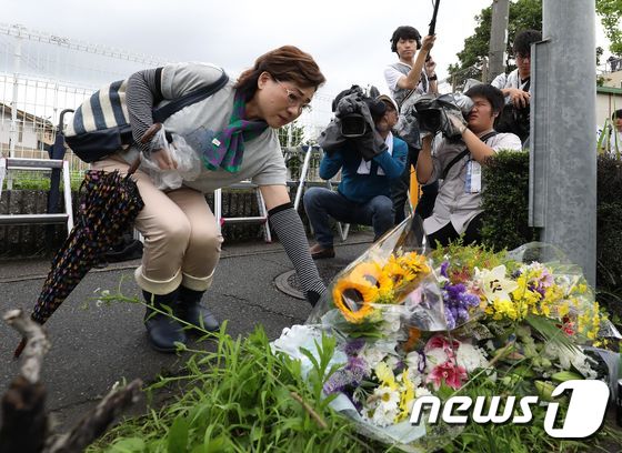 19일 일본 교토애니메이션 방화 참사 현장 앞에 한 시민이 희생자를 추모하는 꽃을 놓고 있다. © AFP=뉴스1