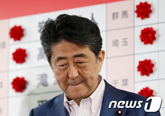 아베 신조 일본 총리가 21일 (현지시간) 도쿄 자민당 당사에서 참의원 선거 당선자 이름 옆에 장미꽃 조화를 붙이고 있다. 자민당은 이날 선거에서 과반의석은 확보했지만 개헌 발의선 유지에는 실패했다. © 로이터=뉴스1
