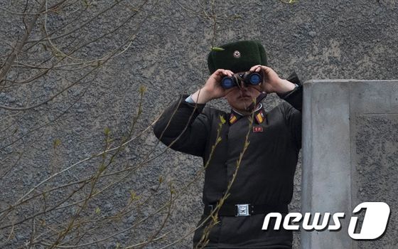 지난 2017년 4월 14일 북한 신의주 인근 압록강에서 북한군 병사 1명이 쌍안경으로 맞은편에 있는 중국 랴오닝성 단둥을 바라보고 있다. © AFP=뉴스1