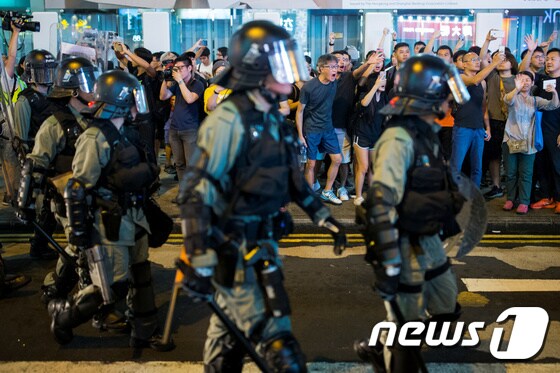 17일 중국 홍콩 몽콕의 나단도로에서 현지인들이 반정부 시위대를 추격하며 전투경찰들에게 함성을 지르고 있다. © 로이터=뉴스1 © News1 이동원 기자