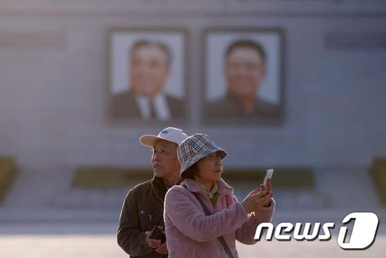 지난 4월 북한 평양시내 김일성광장에서 휴대전화로 사진을 찍고 있는 중국인 관광객들. © AFP=뉴스1