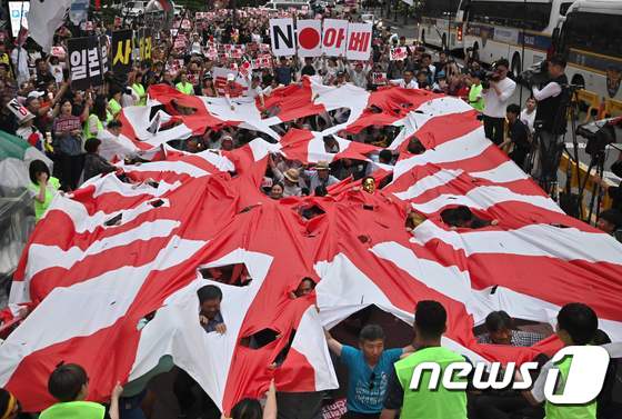 지난 7월20일 서울 일본 대사관 근처에서 열린 반일 집회에서 욱일기(일본이 제2차 세계대전 기간 중 사용한 전범기)를 찢고 있다.  © AFP=뉴스1