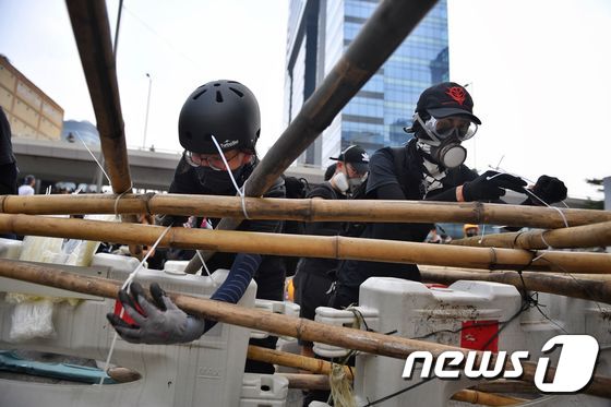 헬멧과 방독면 등으로 무장한 홍콩 반송환법 시위대가 24일(현지시간) 도로를 점거하고 바리게이트를 쌓고 있다. © AFP=뉴스1