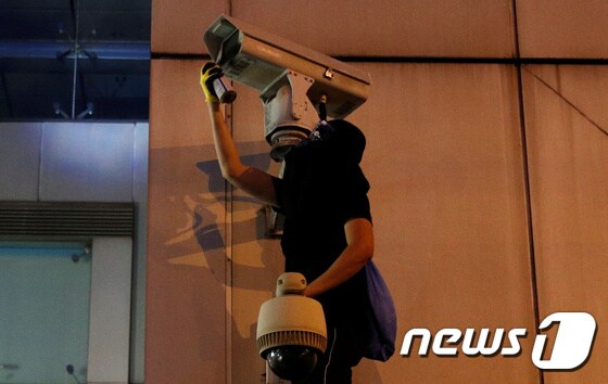홍콩 범죄인 인도법 반대 시위대가 홍콩 주재 중국 연락사무소 앞에 설치된 폐쇄회로(CC)TV에 스프레이를 뿌리고 있다. © 로이터=뉴스1