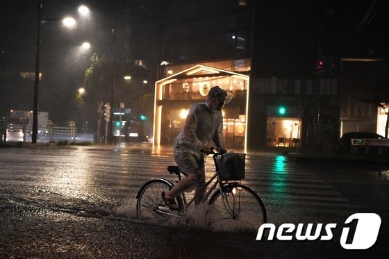 제15호 태풍 '파사이'가 일본 수도권 일대를 강타한 지난 9일 한 남성이 폭우에 잠긴 도쿄 거리에서 자전거를 타고 있다.. © AFP=뉴스1