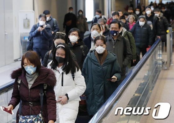 지난 23일 중국 우한발 여객기를 타고 일본 나리타 국제공항에 도착한 승객들이 마스크를 쓴 채 출국작으로 향하고 있다. © 로이터=뉴스1