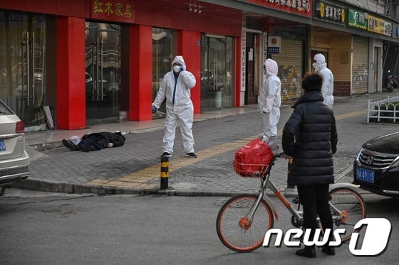 30일 중국 우한 시 한 가구점 앞의 시신을 의료진과 행인이 바라보고 있다. © AFP=뉴스1