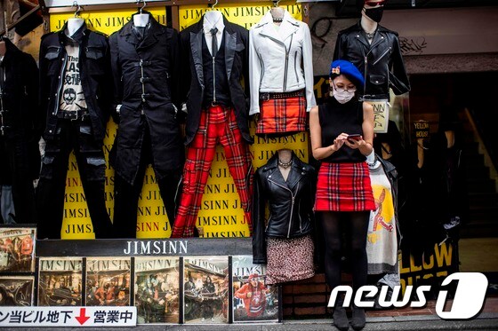 11일 일본 도쿄의 한 옷가게 앞에서 행인이 휴대폰을 만지고 있다. © AFP=뉴스1