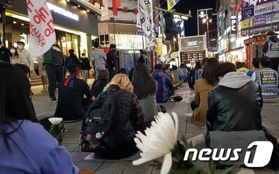 24일 오후 부산 부산진구 서면 하트조형물 앞에서 진행된 택배노동자 과로사 대책마련을 위한 추모문화제에 참여한 시민들이 바닥에 앉아있다. © 뉴스1 조아현 기자