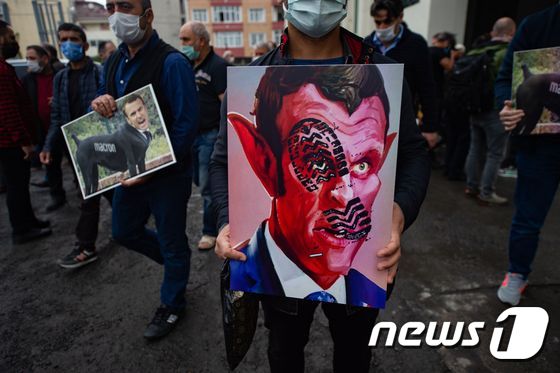 30일(현지시간) 터키 이스탄불에 모인 반프랑스 시위대가 에마뉘엘 마크롱 프랑스 대통령을 악마로 표현한 그림을 들고 행진하고 있다. © AFP=뉴스1
