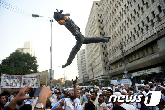 31일 파키스탄에서 반 프랑스 시위대가 에마뉘엘 마크롱 대통령의 인형을 공중에 던지고 있다.  © AFP=뉴스1