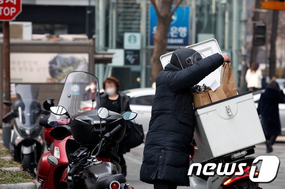 서울 중구 거리에서 한 라이더가 음식을 오토바이 가방에 넣고 있다. 2020.12.23/뉴스1 © News1 이승배 기자