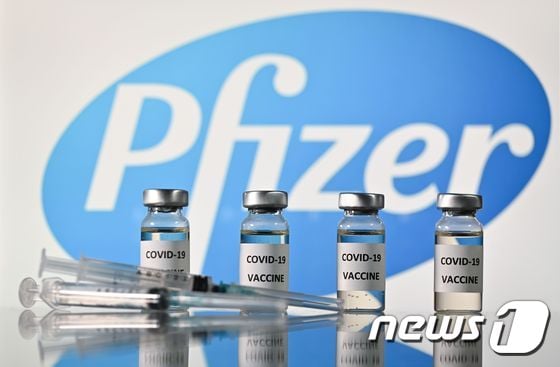  코로나19 백신 스티커가 부착된 병과 미국 제약회사 화이저 로고가 부착된 주사기. © AFP=뉴스1