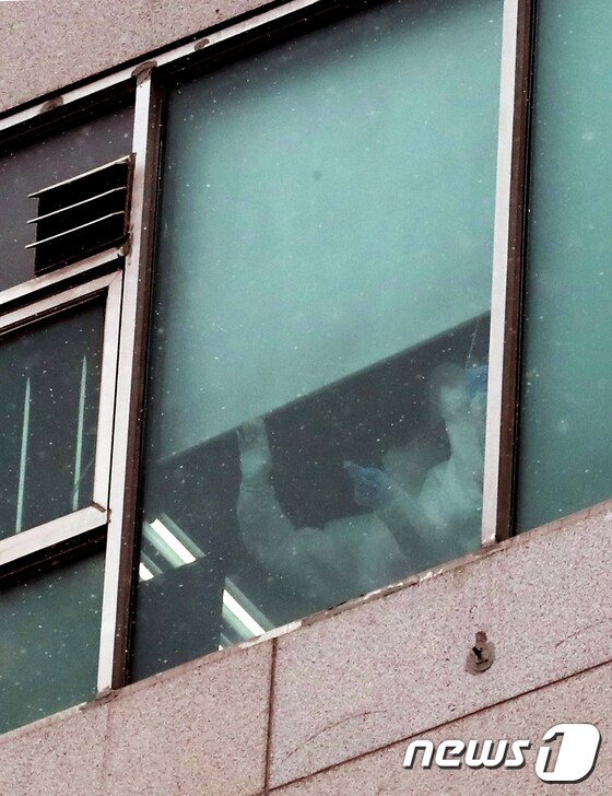   경기 부천시 효플러스요양병원에서 의료관계자들이 창문을 통해 밖을 살펴보고 있다.  /뉴스1 © News1 정진욱 기자