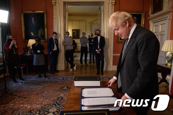 보리스 존슨 영국 총리가 2020년 12월30일(현지시간) 런던 다우닝가 10번지 총리관저에서 영국과 EU의 47년 동거를 끝내는 브렉시트 무역 합의문에 서명을 한 뒤 합의문을 보고 있다. © AFP=뉴스1 © News1 우동명 기자
