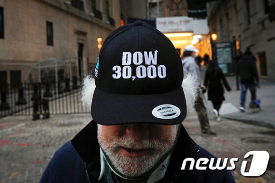 뉴욕증권거래소(NYSE)에서 유명한 주식중개인 피터 터크만이 지난달 뉴욕증시의 다우지수가 3만을 돌파한 기념으로 제작된 모자를 쓰고 있다. © 로이터=뉴스1