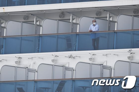 14일 요코하마항에 강제 격리된 채 정박해 있는 다이아몬드 프린세스호에서 마스크를 쓴 승객이 발코니에 나와 있다. © AFP=뉴스1 © News1 우동명 기자