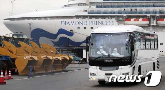 의료용 방호복을 입은 운전자가 운전하는 대형 버스가 지난 14일 국제 크루즈선 '다이아몬드 프린세스'가 정박 중인 일본 요코하마항을 빠져나오고 있다. © 로이터=뉴스1