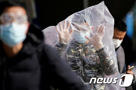 중국 상하이 기차역에서 한 승객이 마스크와 비닐봉지로 자신의 몸을 보호하고 있다. © 로이터=뉴스1 © News1