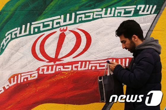 이란 총선을 하루 앞둔 20일(현지시간) 한 남성이 이란 국기가 그려진 벽화 앞을 지나고 있다. © AFP=뉴스1
