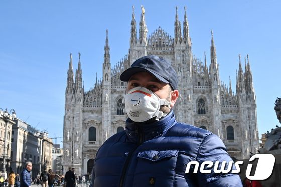 24일 (현지시간) 이탈리아 북부 밀라노에서 신종 코로나바이러스 감염증(코로나19) 우려로 마스크를 착용한 한 시민이 두오모 대성당 앞을 지나가고 있다. © AFP=뉴스1 © News1 송원영 기자