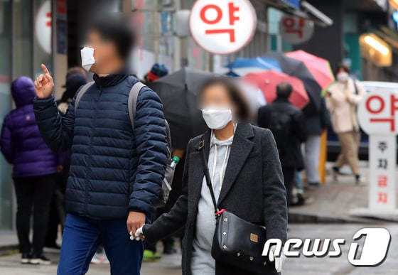 한 예비 부모가 10일 서울 강남구에서 공적마스크를 사려는 시민들로 줄이 길게 늘어선 약국 앞을 지나고 있다. . 2020.3.10/뉴스1 © News1 구윤성 기자