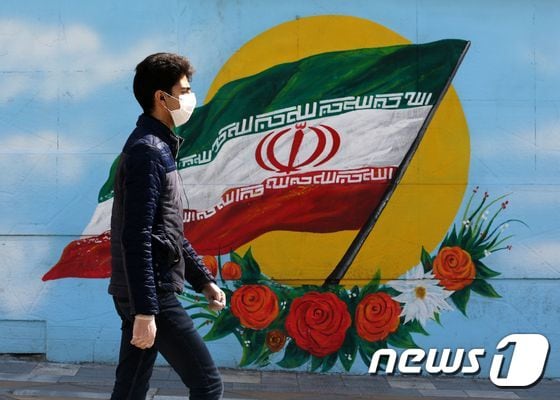 지난 4일(현지시간) 이란 수도 테헤란에서 한 남성이 이란 국기가 그려진 벽화 앞을 지나고 있다. © AFP=뉴스1