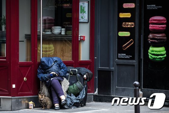 '전 국민 이동금지령'이 발령돼 있는 프랑스 파리 시내에서 21일 한 노숙인이 고양이와 함께 앉아 있다. © AFP=뉴스1