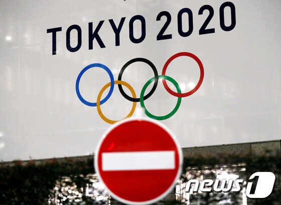23일 일본 도쿄 시내의 한 올림픽 광고판 앞에 정지 표지판이 놓여 있다. © 로이터=뉴스1