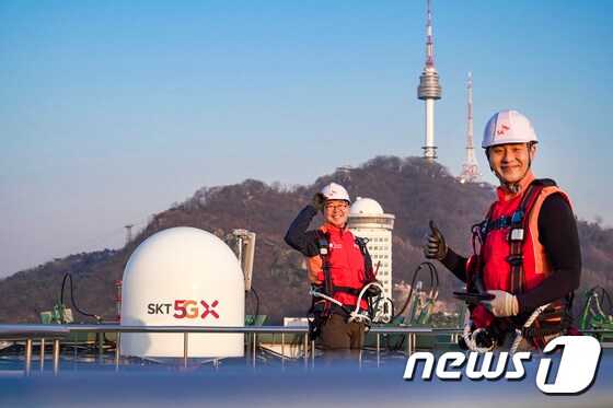 SK텔레콤 홍보모델들이 서울에 위치한 한 빌딩 위에서 5G 기지국을 점검하며 5G 상용화 1주년을 기념해 포즈를 취하고 있다. (SK텔레콤 제공)2020.3.29/뉴스1