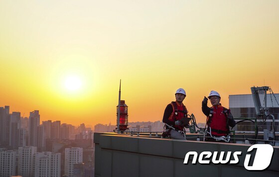SK텔레콤 홍보모델들이 서울에 위치한 한 빌딩 위에서 5G 기지국을 점검하며 포즈를 취하고 있다. (SK텔레콤 제공) 2020.3.29/뉴스1
