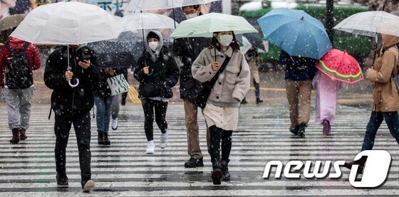 일본 도쿄시민들이 29일 눈 오는 시부야 거리에서 우산을 받쳐 쓰고 마스크를 착용한 채 지나고 있다. © AFP=뉴스1