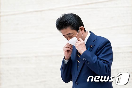 아베 신조 일본 총리가 7일 기자회견 전 마스크를 벗고 있다. © AFP=뉴스1