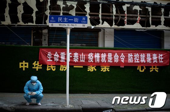 7일 신종 코로나바이러스 감염증(코로나19) 발원지인 중국 후베이(湖北)성 우한(武漢)시에서 보호복을 입은 한 남성이 핸드폰을 들여다보고 있다. © AFP=뉴스1