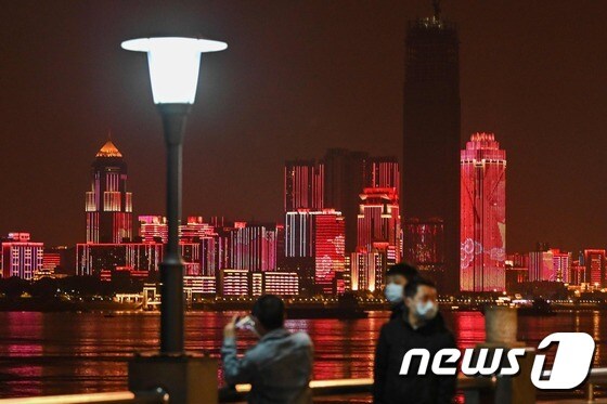 8일 0시를 기해 우한 봉쇄가 풀리자 마스크를 쓴 시민들이 양쯔강변에서 야경을 감상하고 있다. © AFP=뉴스1 © News1 