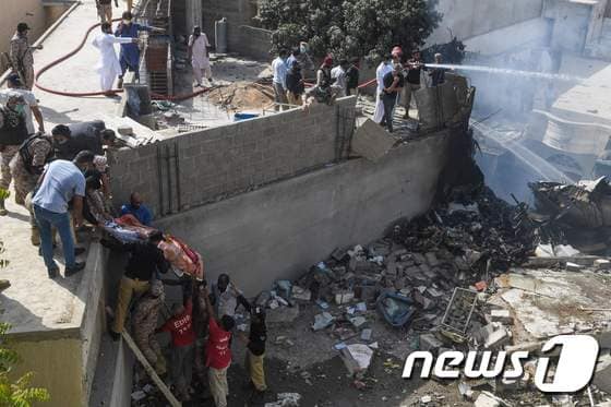 22일 파키스탄 카라치의 한 주거지역에 파키스탄국제항공 여객기가 추락한 현장에서 구조 작업이 이뤄지고 있다. © AFP=뉴스1