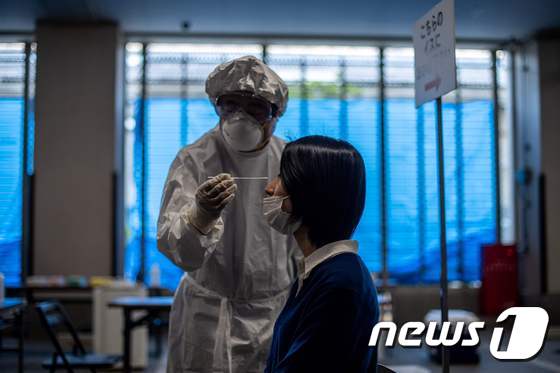 지난 8일 일본 도쿄에서 의료용 방호복을 입은 의료진이 코로나19 검체 채취를 시연하고 있다. © AFP=뉴스1