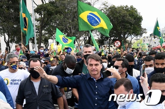 자이르 보우소나루 브라질 대통령이 24일(현지시간) 브라질리아에 있는 대통령 관저 플라날토궁에 도착한 뒤 지지자들에게 인사를 하고 있다. © AFP=뉴스1